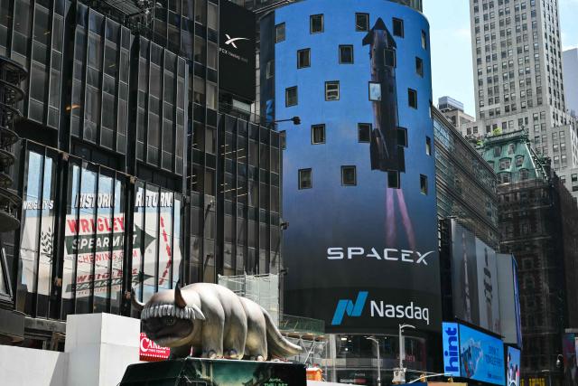 SpaceX advertisements are seen on a digital billboard at the Nasdaq MarketSite in Times Square to celebrate the launch of SpaceXs initial public offering (IPO) in New York on June 12, 2026. Elon Musk's SpaceX begins trading on the Nasdaq exchange on Friday with the biggest initial public offering in history expected to make the polarizing entrepreneur the world's first trillionaire. The company priced more than 555 million shares at $135 each in a filing with the US markets regulator on Thursday, placing SpaceX in the top 10 of Wall Street's biggest companies with a valuation of just under $1.8 trillion -- ahead of Tesla, Facebook-owner Meta and Walmart. (Photo by ANGELA WEISS / AFP)