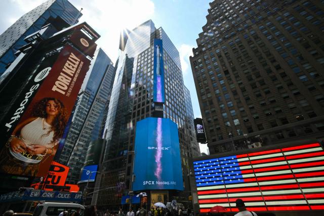 SpaceX advertisements are seen on a digital billboard at the Nasdaq MarketSite in Times Square to celebrate the launch of SpaceXs initial public offering (IPO) in New York on June 12, 2026. Elon Musk's SpaceX begins trading on the Nasdaq exchange on Friday with the biggest initial public offering in history expected to make the polarizing entrepreneur the world's first trillionaire. The company priced more than 555 million shares at $135 each in a filing with the US markets regulator on Thursday, placing SpaceX in the top 10 of Wall Street's biggest companies with a valuation of just under $1.8 trillion -- ahead of Tesla, Facebook-owner Meta and Walmart. (Photo by ANGELA WEISS / AFP)