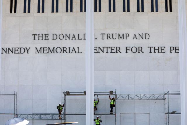 Workers stand on scaffolding near the signage for the Donald J. Trump and John F. Kennedy Memorial Center for the Performing Arts in Washington, DC, on June 12, 2026. A US federal judge on Friday rejected a bid by the board of the Kennedy Center and the Justice Department to halt the removal of President Donald Trump's name from the performing arts venue. District Judge Christopher Cooper, in a ruling last month, ordered Trump's name taken off the iconic building in the nation's capital by Friday, June 12, 2026. (Photo by Alex WROBLEWSKI / AFP)