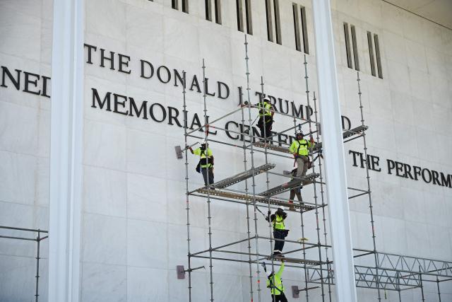 Workers stand on scaffolding near the signage for the Donald J. Trump and John F. Kennedy Memorial Center for the Performing Arts in Washington, DC, on June 12, 2026. A US federal judge on Friday rejected a bid by the board of the Kennedy Center and the Justice Department to halt the removal of President Donald Trump's name from the performing arts venue. District Judge Christopher Cooper, in a ruling last month, ordered Trump's name taken off the iconic building in the nation's capital by Friday, June 12, 2026. (Photo by Alex WROBLEWSKI / AFP)