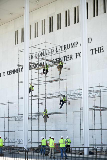 Workers stand on scaffolding near the signage for the Donald J. Trump and John F. Kennedy Memorial Center for the Performing Arts in Washington, DC, on June 12, 2026. A US federal judge on Friday rejected a bid by the board of the Kennedy Center and the Justice Department to halt the removal of President Donald Trump's name from the performing arts venue. District Judge Christopher Cooper, in a ruling last month, ordered Trump's name taken off the iconic building in the nation's capital by Friday, June 12, 2026. (Photo by Alex WROBLEWSKI / AFP)