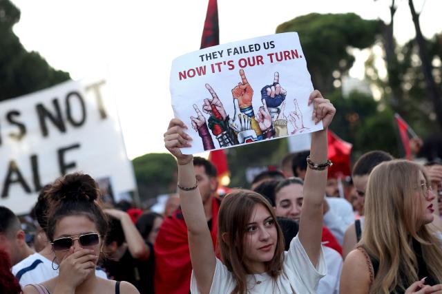 A protestor (C) holds a placard reading "They failed us - Now it's our turn." as they gather in front of Albania's Prime Minister's Office during the 13th day of demonstration against the construction of a luxury resort near a protected natural area, in Tirana on June 12, 2026. Several thousand citizens demonstrated in Tirana, 13 days in row after the first protest repressed on Zvernec beach, to demand transparency around a tourist complex project allegedly linked to US President's son-in-law, Kushner. The demonstrators argue that the estimated $1.2 billion project, led by Kushner and his wife Ivanka, will harm the environment, with plans for luxury hotels in the protected area of Vjosa-Narta on the southern coast. (Photo by Adnan Beci / AFP)