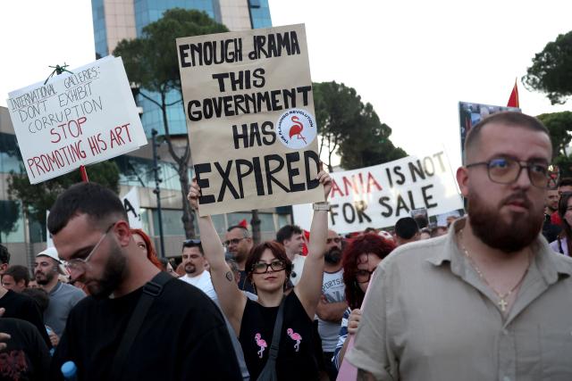 A protestor (C) holds a placard reading "Enough Rama - This government has expired" as they gather in front of Albania's Prime Minister's Office during the 13th day of demonstration against the construction of a luxury resort near a protected natural area, in Tirana on June 12, 2026. Several thousand citizens demonstrated in Tirana, 13 days in row after the first protest repressed on Zvernec beach, to demand transparency around a tourist complex project allegedly linked to US President's son-in-law, Kushner. The demonstrators argue that the estimated $1.2 billion project, led by Kushner and his wife Ivanka, will harm the environment, with plans for luxury hotels in the protected area of Vjosa-Narta on the southern coast. (Photo by Adnan Beci / AFP)