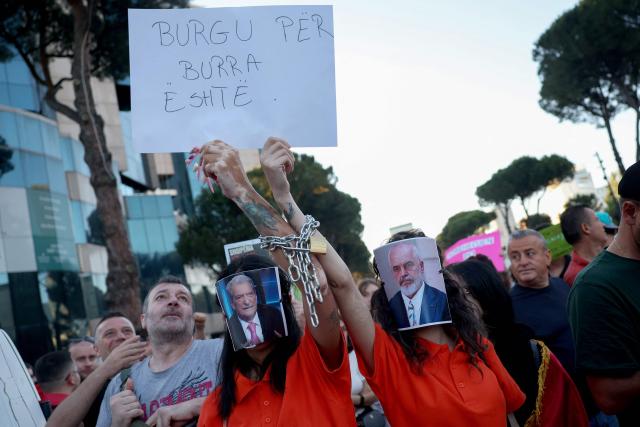 Protestors with their faces covered by images depicting Albania's Prime Minister Edi Rama (R) and Albanian opposition leader Sali Berisha gather in front of Albania's Prime Minister's Office during the 13th day of demonstration against the construction of a luxury resort near a protected natural area, in Tirana on June 12, 2026. Several thousand citizens demonstrated in Tirana, 13 days in row after the first protest repressed on Zvernec beach, to demand transparency around a tourist complex project allegedly linked to US President's son-in-law, Kushner. The demonstrators argue that the estimated $1.2 billion project, led by Kushner and his wife Ivanka, will harm the environment, with plans for luxury hotels in the protected area of Vjosa-Narta on the southern coast. (Photo by Adnan Beci / AFP)