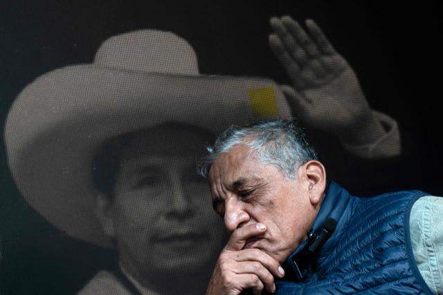 Antauro Humala, leader and founder of the Ethnocacerist party and promoter of Peruvian ultranationalism, gestures in front of an image of former Peru's President Pedro Castillo during an interview with AFP at the Ethnocacerist headquarters in Lima on June 12, 2026. Peru is heading toward a deeper governance crisis and protests if right-wing candidate Keiko Fujimori prevails over leftist Roberto Sanchez in the tight presidential vote count, nationalist leader Antauro Humala told AFP on June 12. (Photo by Ernesto BENAVIDES / AFP)
