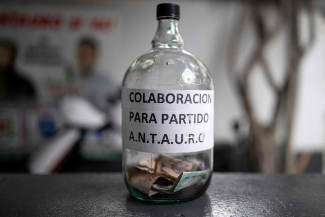 A bottle with a sign that reads "Collaboration for the A.N.T.A.U.R.O party" is seen during an interview with Antauro Humala, leader and founder of the Ethnocacerist party and promoter of Peruvian ultranationalism, at the Ethnocacerist party headquarters in Lima on June 12, 2026. Peru is heading toward a deeper governance crisis and protests if right-wing candidate Keiko Fujimori prevails over leftist Roberto Sanchez in the tight presidential vote count, nationalist leader Antauro Humala told AFP on June 12. (Photo by Ernesto BENAVIDES / AFP)