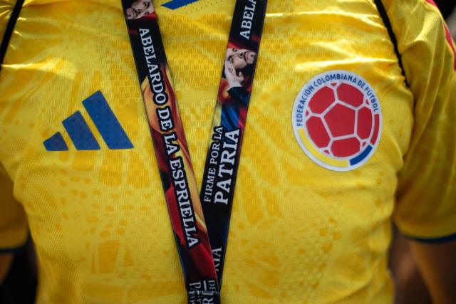 (FILES) A supporter of Colombia's presidential candidate Abelardo de la Espriella, from the Defensores de la Patria political movement, wears a Colombia national football team jersey and a campaign lanyard during a "Banderazo" in Bogota on June 6, 2026. The Colombian Supreme Court of Justice suspended on June 12, 2026 a lower court’s ruling that had banned far-right presidential candidate Abelardo de la Espriella from using national symbols and his signature slogan, “Firm for the homeland”. The 47-year-old lawyer often uses the military salute of the armed forces and national insignia at political rallies, which are filled with Colombian flags and national football team shirts. Colombia will hold the runoff presidential election on June 21. (Photo by ESTEBAN VEGA LA-ROTTA / AFP)