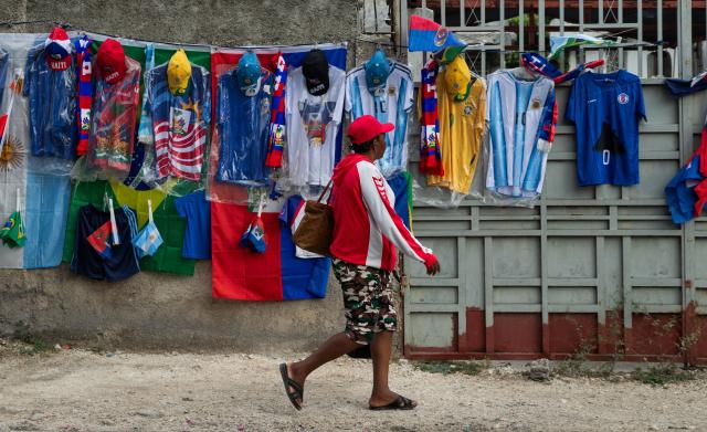 This photo taken on June 11, 2026 shows a woman walking past jerseys for sale in Port-au-Prince, Haiti. The 2026 World Cup football tournament kicked off in Mexico City on June 11. (Photo by Clarens SIFFROY / AFP)