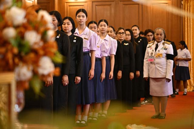 Members of the public (in black) and officials (in white) pay respects in front of a portrait of the late Thai Princess Bajrakitiyabha Mahidol in the royal throne hall at the Grand Palace in Bangkok on June 13, 2026. Thai Princess Bajrakitiyabha Mahidol, the king's eldest daughter, has died aged 47, the royal palace announced on June 12, more than three years after she was hospitalised following a sudden illness. (Photo by ANTHONY WALLACE / AFP)