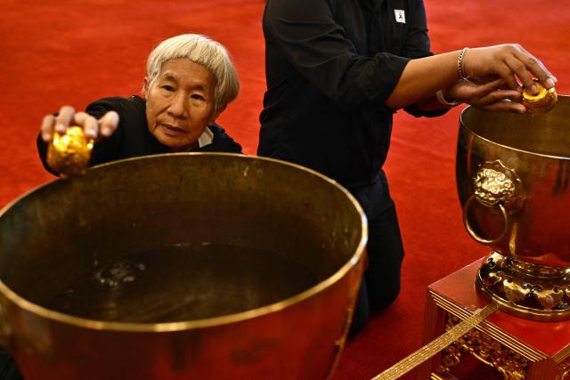 A member of the public dips a cup while paying respects in front of a portrait of the late Thai Princess Bajrakitiyabha Mahidol in the royal throne hall at the Grand Palace in Bangkok on June 13, 2026. Thai Princess Bajrakitiyabha Mahidol, the king's eldest daughter, has died aged 47, the royal palace announced on June 12, more than three years after she was hospitalised following a sudden illness. (Photo by ANTHONY WALLACE / AFP)