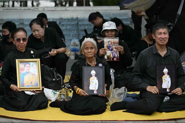 Mourners hold photos of late Thai Princess Bajrakitiyabha Mahidol outside the Grand Palace in Bangkok on June 13, 2026. Hundreds of black-clad Thai mourners gathered at the royal palace in Bangkok on June 13, awaiting the arrival of the body of the king's eldest daughter a day after her death was announced. (Photo by Lillian SUWANRUMPHA / AFP)