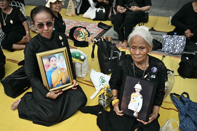 Mourners hold photos of late Thai Princess Bajrakitiyabha Mahidol outside the Grand Palace in Bangkok on June 13, 2026. Hundreds of black-clad Thai mourners gathered at the royal palace in Bangkok on June 13, awaiting the arrival of the body of the king's eldest daughter a day after her death was announced. (Photo by Lillian SUWANRUMPHA / AFP)
