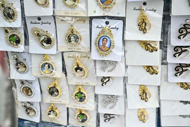 Pins with the images of late Thai Princess Bajrakitiyabha Mahidol and members of the Thai royal family are pictured for sale outside the Grand Palace in Bangkok on June 13, 2026. Hundreds of black-clad Thai mourners gathered at the royal palace in Bangkok on June 13, awaiting the arrival of the body of the king's eldest daughter a day after her death was announced. (Photo by Lillian SUWANRUMPHA / AFP)