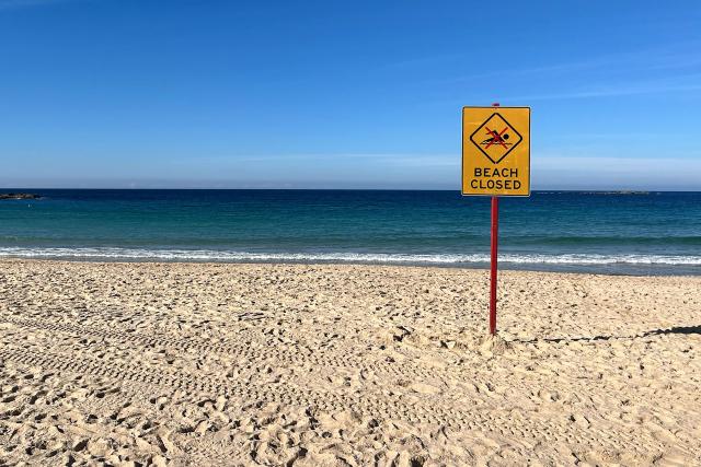 A beach closed sign is displayed at Coogee Beach in Sydney on June 13, 2026. Beachgoers dragged a badly injured swimmer from the water at Coogee, one of Australia's most beloved beaches and popular spot for tourists, after she was mauled by a shark on June 13, police said. Four people have been killed in an unusual spate of shark attacks around Australia this year. (Photo by OLIVER HOTHAM / AFP)