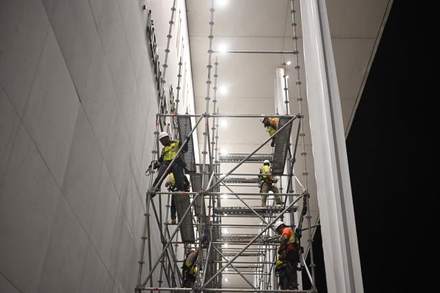 Workers build scaffolding near the signage for the "Donald J. Trump and John F. Kennedy Memorial Center for the Performing Arts" in Washington, DC, early on June 13, 2026. A US federal judge on June 12 rejected a bid by the board of the Kennedy Center and the Justice Department to halt the removal of President Donald Trump's name from the performing arts venue. District Judge Christopher Cooper, in a ruling last month, ordered Trump's name taken off the iconic building in the nation's capital by Friday, June 12, 2026. (Photo by Alex WROBLEWSKI / AFP)