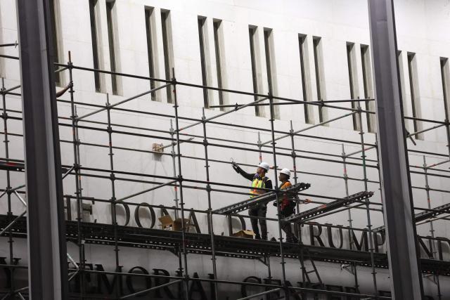 Workers build scaffolding near the signage for the "Donald J. Trump and John F. Kennedy Memorial Center for the Performing Arts" in Washington, DC, early on June 13, 2026. A US federal judge on June 12 rejected a bid by the board of the Kennedy Center and the Justice Department to halt the removal of President Donald Trump's name from the performing arts venue. District Judge Christopher Cooper, in a ruling last month, ordered Trump's name taken off the iconic building in the nation's capital by Friday, June 12, 2026. (Photo by Alex WROBLEWSKI / AFP)