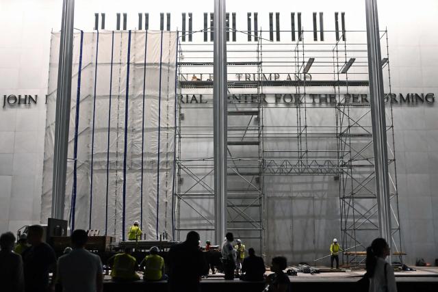 Workers build scaffolding and hang flame retardant tarps near the signage for the "Donald J. Trump and John F. Kennedy Memorial Center for the Performing Arts" in Washington, DC, early on June 13, 2026. A US federal judge on June 12 rejected a bid by the board of the Kennedy Center and the Justice Department to halt the removal of President Donald Trump's name from the performing arts venue. (Photo by Alex WROBLEWSKI / AFP)