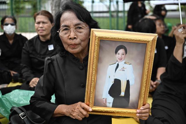 A mourner holds a portrait of late Thai Princess Bajrakitiyabha Mahidol outside the Grand Palace in Bangkok on June 13, 2026. Hundreds of black-clad Thai mourners gathered at the royal palace in Bangkok on June 13, awaiting the arrival of the body of the king's eldest daughter a day after her death was announced. (Photo by Lillian SUWANRUMPHA / AFP)