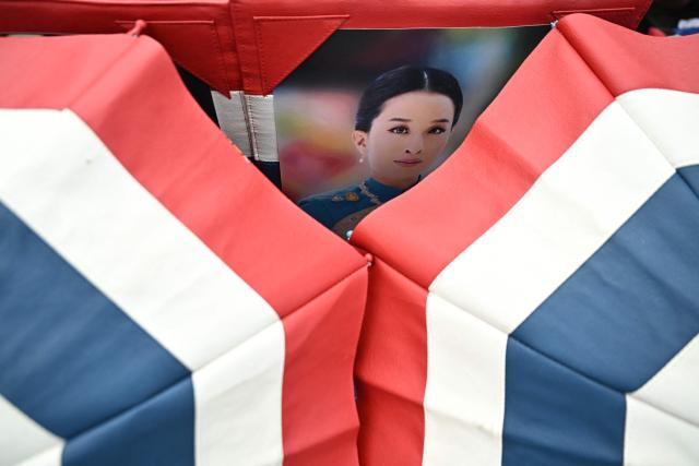 A photo of Thai Princess Bajrakitiyabha Mahidol is pictured outside the Grand Palace in Bangkok on June 13, 2026. Hundreds of black-clad Thai mourners gathered at the royal palace in Bangkok on June 13, awaiting the arrival of the body of the king's eldest daughter a day after her death was announced. (Photo by Lillian SUWANRUMPHA / AFP)