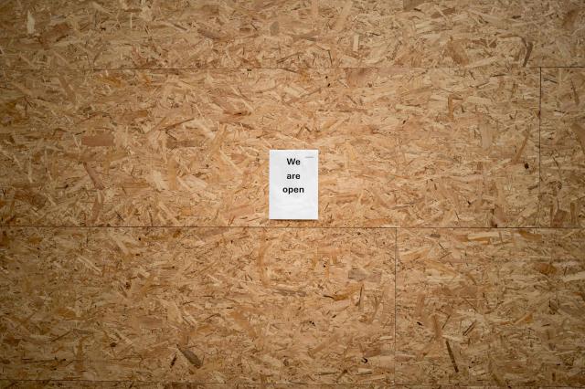 This photograph shows a sign reading "We are open" placed on wooden panels installed to protect a shop ahead of demonstrations against the nearby G7 summit in Évian, in Geneva, June 12, 2026. Protests against the G7 summit in Evian are set to take place in nearby Geneva, where activists can gather more easily than in the tightly secured host town. (Photo by Fabrice COFFRINI / AFP)