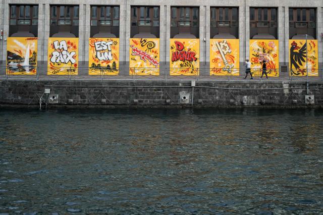 This photograph shows the Banque Cantonale de Geneve (Geneva Cantonal Bank) boarded up with graffiti-covered wooden panels to protect the facade ahead of demonstrations against the nearby G7 summit in Evian, in Geneva, on June 12, 2026. Protests against the G7 summit in Evian are set to take place in nearby Geneva, where activists can gather more easily than in the tightly secured host town. (Photo by Fabrice COFFRINI / AFP)