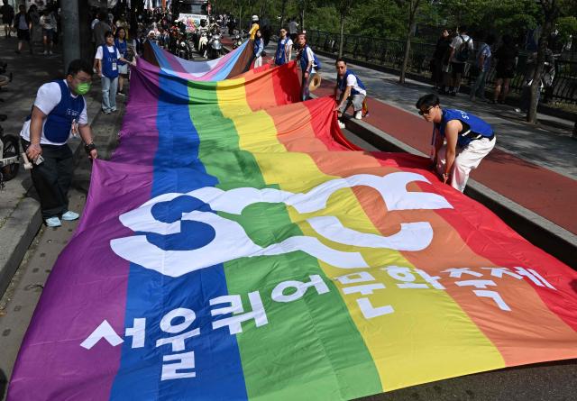 Staff members carry a huge flag during a Pride event in support of LGBTQ rights as part of the Seoul Queer Culture Festival in Seoul on June 13, 2026. (Photo by Jung Yeon-je / AFP)