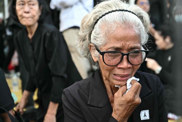 A mourner cries as the hearse carrying the body of Thai Princess Bajrakitiyabha Mahidol arrives at the Grand Palace as mourners line the motorcade route, where funeral rites will begin for the late princess, in Bangkok on June 13, 2026. Hundreds of black-clad Thai mourners gathered at the royal palace in Bangkok on June 13, awaiting the arrival of the body of the king's eldest daughter a day after her death was announced. (Photo by Lillian SUWANRUMPHA / AFP)