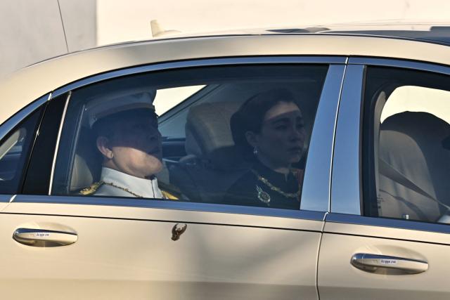 Thai King Maha Vajiralongkorn and Queen Suthida are seen in a car ahead of the hearse carrying the body of Thai Princess Bajrakitiyabha Mahidol to the Grand Palace, where funeral rites will begin for the late princess, in Bangkok on June 13, 2026. Hundreds of black-clad Thai mourners gathered at the royal palace in Bangkok on June 13, awaiting the arrival of the body of the king's eldest daughter a day after her death was announced. (Photo by Lillian SUWANRUMPHA / AFP)