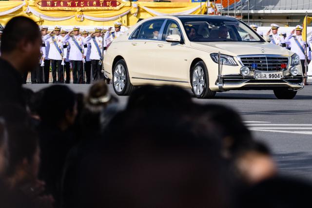 Thai King Maha Vajiralongkorn and Queen Suthida are seen in a car ahead of the hearse carrying the body of Thai Princess Bajrakitiyabha Mahidol to the Grand Palace, where funeral rites will begin for the late princess, in Bangkok on June 13, 2026. Hundreds of black-clad Thai mourners gathered at the royal palace in Bangkok on June 13, awaiting the arrival of the body of the king's eldest daughter a day after her death was announced. (Photo by ANTHONY WALLACE / AFP)
