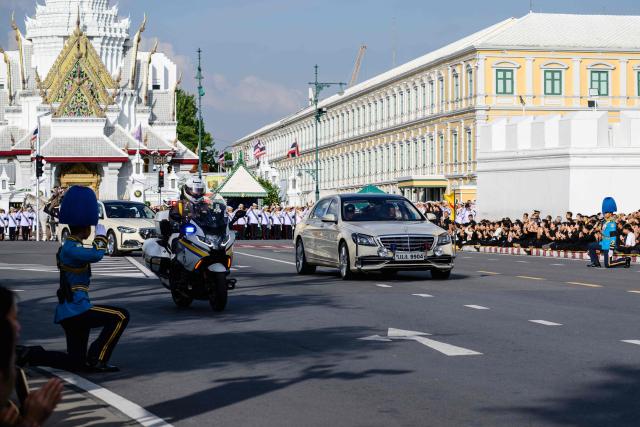 Thai King Maha Vajiralongkorn and Queen Suthida are seen in a car ahead of the hearse carrying the body of Thai Princess Bajrakitiyabha Mahidol to the Grand Palace, where funeral rites will begin for the late princess, in Bangkok on June 13, 2026. Hundreds of black-clad Thai mourners gathered at the royal palace in Bangkok on June 13, awaiting the arrival of the body of the king's eldest daughter a day after her death was announced. (Photo by ANTHONY WALLACE / AFP)
