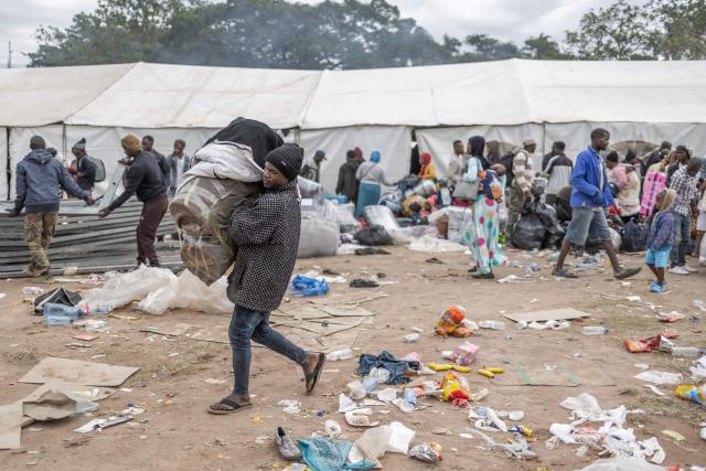 Displaced migrants gathered at Sherwood Park in Durban on June 13, 2026 carry their belongings as they wait to be repatriated to Malawi after fleeing their homes amid fears of xenophobic attacks. Hundreds of migrants await repatriation to Malawi from South Africa following xenophobic violence in the country. (Photo by RAJESH JANTILAL / AFP)