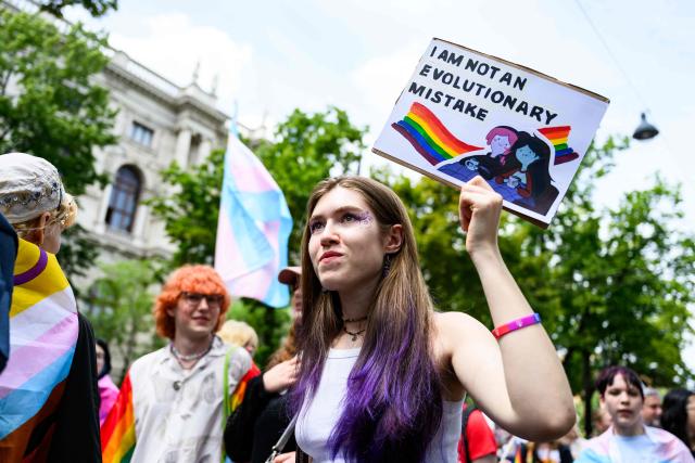 a participant holds a sign reading "I am not an evolutionary mistake" during the 30th edition of the Vienna Pride Parade or Rainbow Parade in Vienna on June 13, 2026. The parade is an important political demonstration advocating for the rights of lesbian, gay, bisexual, transgender, intersex and queer people, according to organisers. (Photo by MAX SLOVENCIK / APA / AFP) / Austria OUT