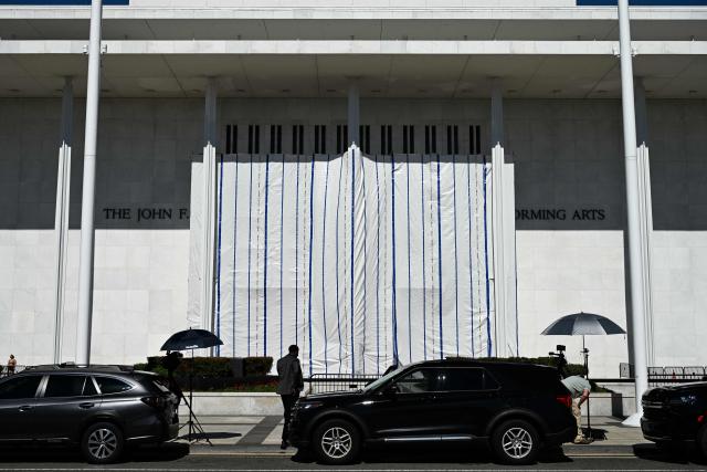 A tarp covers the facade of the John F. Kennedy Memorial Center for the Performing Arts in Washington, DC, on June 13, 2026. Workers began removing President Donald Trump's name from the facade of the John F. Kennedy Center for the Performing Arts on Saturday, after a federal judge ruled that its renaming was unlawful. The effort came after a judge rejected a last-minute bid by the center's board to halt the removal of Trump's name. (Photo by Alex WROBLEWSKI / AFP)
