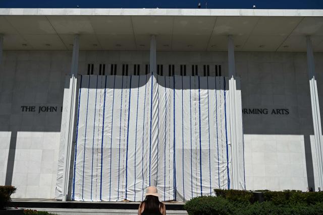 A tarp covers the facade of the John F. Kennedy Memorial Center for the Performing Arts in Washington, DC, on June 13, 2026. Workers began removing President Donald Trump's name from the facade of the John F. Kennedy Center for the Performing Arts on Saturday, after a federal judge ruled that its renaming was unlawful. The effort came after a judge rejected a last-minute bid by the center's board to halt the removal of Trump's name. (Photo by Alex WROBLEWSKI / AFP)