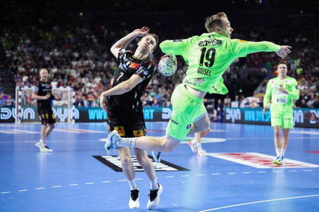 Fuechse Berlin's Danish right back #19 Mathias Gidsel (R) and Magdeburg's Swedish centre back #07 Felix Claar (L) vie for the ball during the EHF Men's Handball Champions League semi-final match between SC Magdeburg and Fuechse Berlin in Cologne, western Germany on June 13, 2026. (Photo by Ronny HARTMANN / AFP)