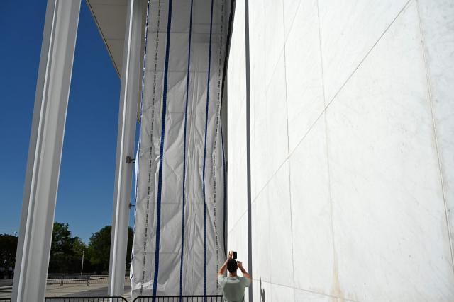 A tarp covers the facade of the John F. Kennedy Memorial Center for the Performing Arts in Washington, DC, on June 13, 2026. Workers began removing President Donald Trump's name from the facade of the John F. Kennedy Center for the Performing Arts on Saturday, after a federal judge ruled that its renaming was unlawful. The effort came after a judge rejected a last-minute bid by the center's board to halt the removal of Trump's name. (Photo by Alex WROBLEWSKI / AFP)