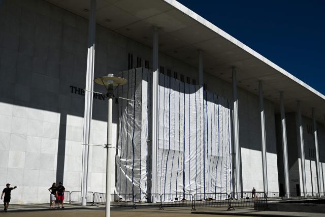 A tarp covers the facade of the John F. Kennedy Memorial Center for the Performing Arts in Washington, DC, on June 13, 2026. Workers began removing President Donald Trump's name from the facade of the John F. Kennedy Center for the Performing Arts on Saturday, after a federal judge ruled that its renaming was unlawful. The effort came after a judge rejected a last-minute bid by the center's board to halt the removal of Trump's name. (Photo by Alex WROBLEWSKI / AFP)