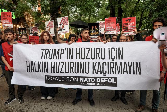Demonstrators hold placards reading "Don’t disrupt the public’s peace for Trump’s sake" during a rally against the upcoming NATO Summit early July in Ankara, on June 13, 2026. US Secretary of State confirmed the US President would attend the July 7-8 summit in the Turkish capital, as concerns linger about Washington's commitment to the transatlantic alliance. (Photo by Adem ALTAN / AFP)
