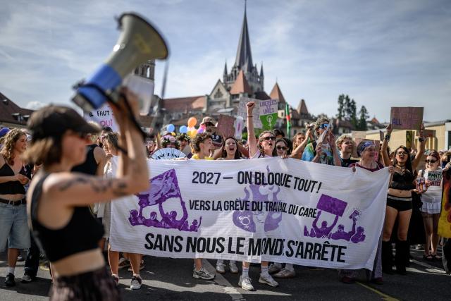 Protesters hold a banner reading "2027 - we block everything; without us the world stops" as they take part in a feminist strike against patriarchy and the upcoming G7 summit in nearby Evian, in Lausanne on June 13, 2026. (Photo by Fabrice COFFRINI / AFP)