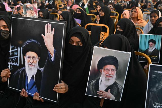 Activists carry portraits of Iran’s slain supreme leader Ayatollah Ali Khamenei, as they pay tribute at Minar-e-Pakistan in Lahore on June 13, 2026, during the Shaheed-e-Ummat conference. (Photo by Arif Ali / AFP)