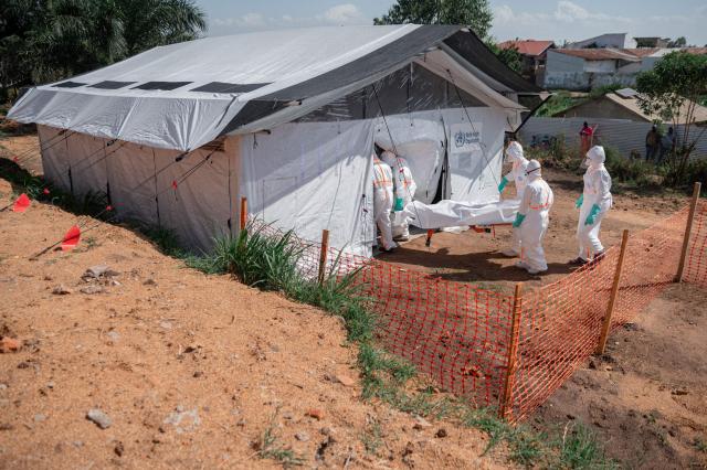 EDITORS NOTE: Graphic content / Members of specialized response teams enter the morgue of the Evangelical Medical Center of Nyankunde (CME) with the body of a person who died from Ebola virus disease to allow relatives to pay their last respects after washing, disinfection and safe body-wrapping procedures in Bunia, Ituri Province, Democratic Republic of Congo, on June 13, 2026. (Photo by Jospin Mwisha / AFP)