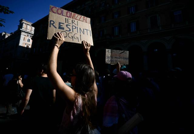 An anti-fascist demonstrators holds a sign reading "Once colonised now rejected" against remigration as they march against a rally organised by right-wing groups advocating "remigration", in Rome on June 13, 2026. (Photo by Filippo MONTEFORTE / AFP)
