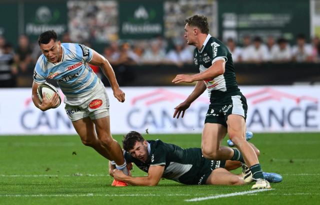 Racing 92' New Zaeland center Joseph Manu (L) is tackled by Pau's French centre Fabien Brau-Boirie (C) during the French Top14 rugby union playoff match between Section Paloise Bearn Pyrenees (Pau) and Racing 92 at Stade du Hameau in Pau, south-western France on June 13, 2026. (Photo by Gaizka IROZ / AFP)
