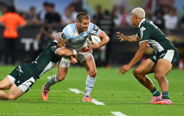 Racing 92' French fly-half Antoine Gibert (C) is tackled by Pau's English scrum-half Dan Robson (L) during the French Top14 rugby union playoff match between Section Paloise Bearn Pyrenees (Pau) and Racing 92 at Stade du Hameau in Pau, south-western France on June 13, 2026. (Photo by Gaizka IROZ / AFP)