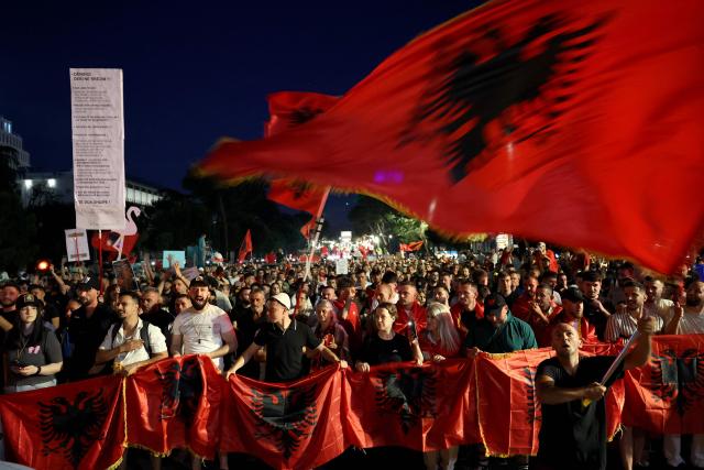 Protestors hold national flags as they gather in front of Albania's Prime Minister's Office, in Tirana, on June 13, 2026 during a demonstration against the construction of a luxury resort near a protected natural area of Zvernec near Vlore. Several thousand citizens demonstrated in Tirana, 14 days in row after the first protest  repressed on Zvernec beach, to demand transparency around a tourist complex project allegedly linked to US President's son-in-law, Jared Kushner. The demonstrators argue that the estimated $1.2 billion project, led by Kushner and his wife Ivanka, will harm the environment, with plans for luxury hotels in the protected area of Vjosa-Narta on the southern coast. (Photo by Adnan Beci / AFP)