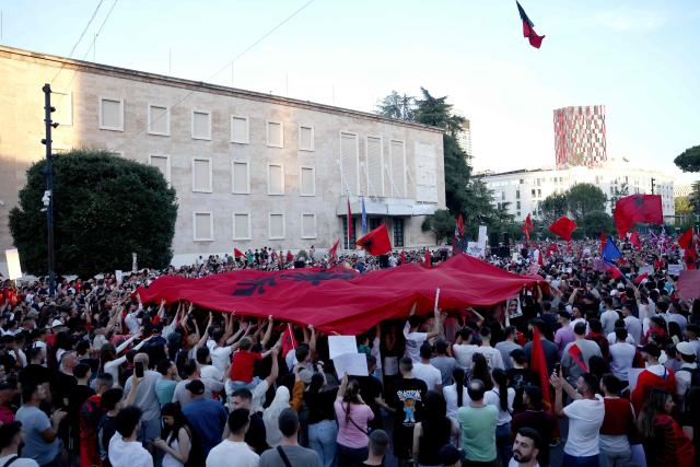 Protestors hold national flags as they gather in front of Albania's Prime Minister's Office, in Tirana, on June 13, 2026 during a demonstration against the construction of a luxury resort near a protected natural area of Zvernec near Vlore. Several thousand citizens demonstrated in Tirana, 14 days in row after the first protest  repressed on Zvernec beach, to demand transparency around a tourist complex project allegedly linked to US President's son-in-law, Jared Kushner. The demonstrators argue that the estimated $1.2 billion project, led by Kushner and his wife Ivanka, will harm the environment, with plans for luxury hotels in the protected area of Vjosa-Narta on the southern coast. (Photo by Adnan Beci / AFP)
