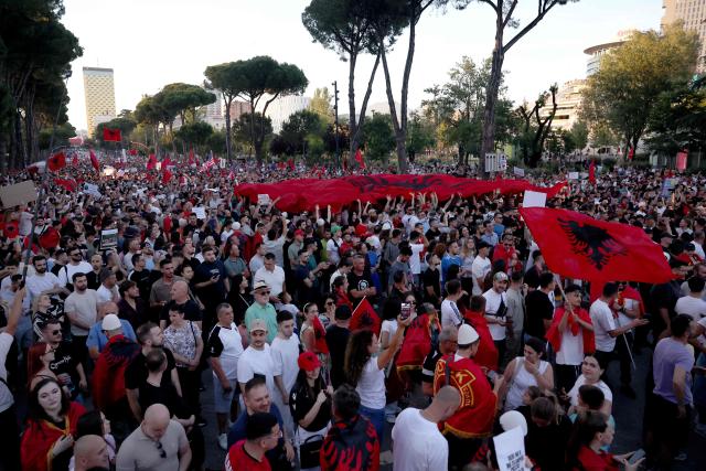 Protestors hold national flags as they gather in front of Albania's Prime Minister's Office, in Tirana, on June 13, 2026 during a demonstration against the construction of a luxury resort near a protected natural area of Zvernec near Vlore. Several thousand citizens demonstrated in Tirana, 14 days in row after the first protest  repressed on Zvernec beach, to demand transparency around a tourist complex project allegedly linked to US President's son-in-law, Jared Kushner. The demonstrators argue that the estimated $1.2 billion project, led by Kushner and his wife Ivanka, will harm the environment, with plans for luxury hotels in the protected area of Vjosa-Narta on the southern coast. (Photo by Adnan Beci / AFP)