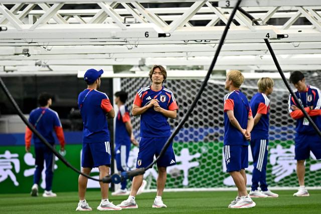 Japan's defender #04 Kou Itakura (C) looks on under heat lamps as they walk with teammates on the pitch at Dallas Stadium on the eve of the 2026 World Cup football tournament Group F football match against Netherlands in Dallas on June 13, 2026.  (Photo by Paul ELLIS / AFP)