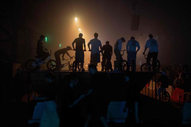 Young men perform bike tricks during "BRUDNY PES" (dirty dog), a multi-genre music festival independent music and street culture, at the Dovzhenko Film Studio in Kyiv on June 13, 2026, amid the Russian invasion of Ukraine. The festival will raffle off a car for donations in support of the Armed Forces of Ukraine. All funds raised will go toward purchasing drones. Since 2023, the festival has partnered with the "Khvostati" animal shelter, selecting a new dog each year to serve as the festivals mascot. Its photo is featured on the main poster, and seeks to find it a home. (Photo by Tetiana DZHAFAROVA / AFP)
