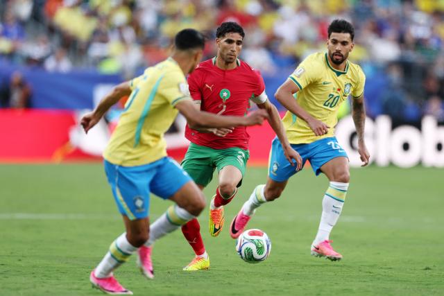 Morocco's defender #02 Achraf Hakimi (C) runs with the ball past Brazil's midfielder #20 Lucas Paqueta (R) during the 2026 World Cup Group C football match between Brazil and Morocco at the New York/New Jersey Stadium in East Rutherford on June 13, 2026. (Photo by CHARLY TRIBALLEAU / AFP)